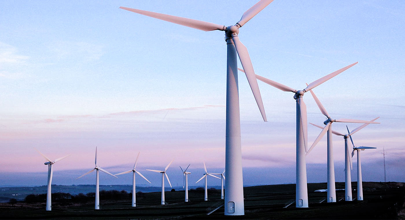 white wind turbines in a field with a blue pink sky
